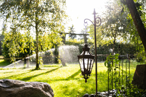 Garten mit grünen Wiesen und Rasensprenger