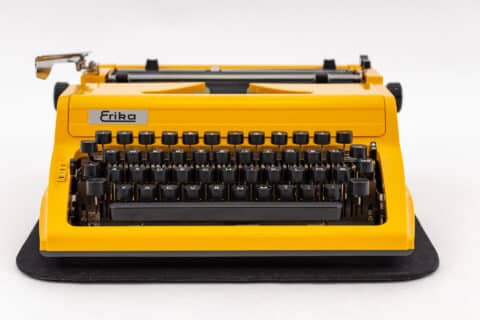 Eine gelbe Erika Schreibmaschine steht im Mittelpunkt des Fotos und erinnert an die Anfänge der Schreibtechnologie