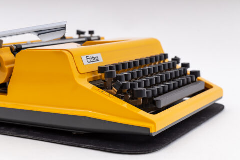 Eine gelbe Erika Schreibmaschine steht im Mittelpunkt des Fotos und erinnert an die Anfänge der Schreibtechnologie